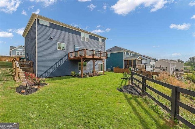 rear view of house featuring a lawn, a deck, a residential view, stairway, and fence