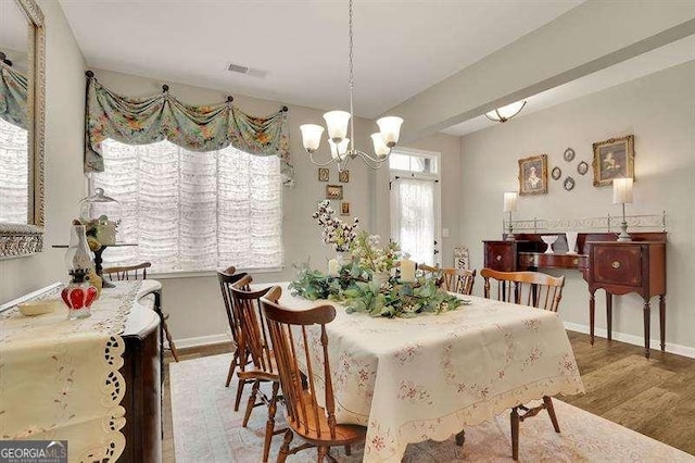 dining room featuring baseboards, an inviting chandelier, wood finished floors, and visible vents