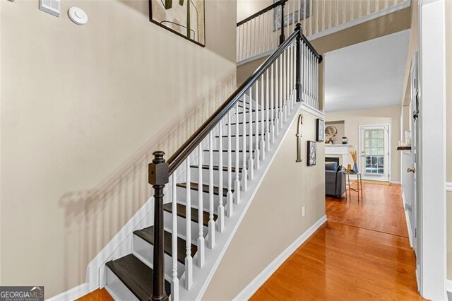 stairs featuring baseboards, wood finished floors, visible vents, and a fireplace