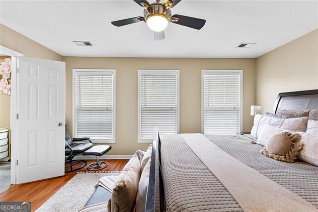 bedroom with a ceiling fan, baseboards, visible vents, and wood finished floors