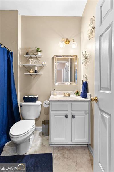 bathroom featuring tile patterned flooring, vanity, toilet, baseboards, and a shower with curtain