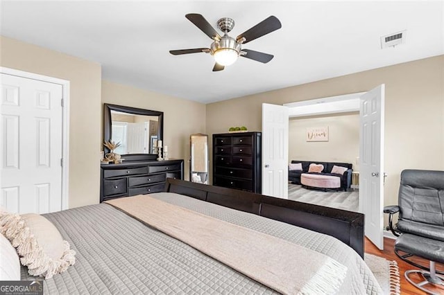 bedroom with a ceiling fan, wood finished floors, and visible vents