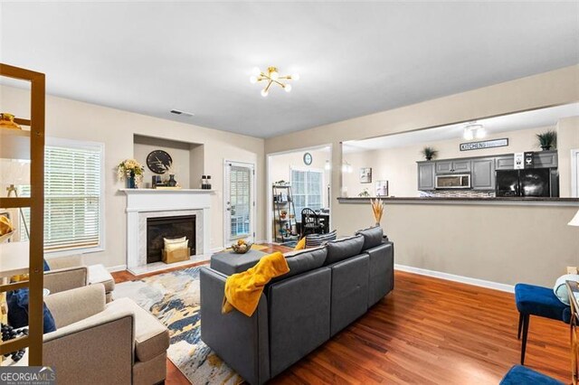 living room with baseboards, visible vents, wood finished floors, and a high end fireplace