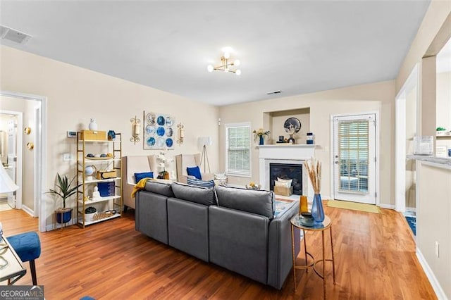 living room with visible vents, a glass covered fireplace, wood finished floors, and a healthy amount of sunlight