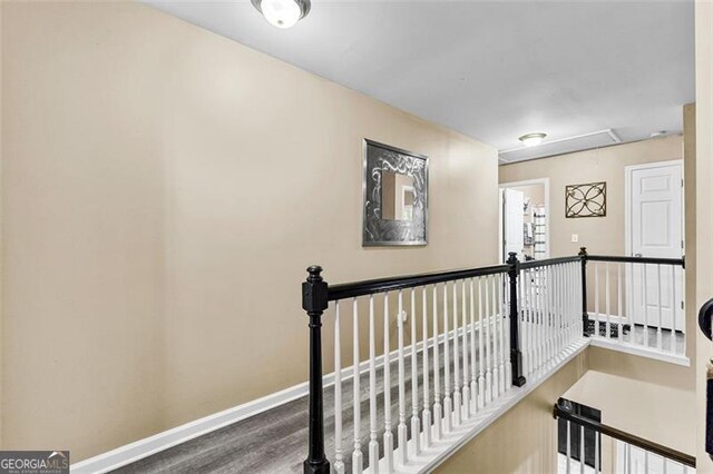 corridor featuring baseboards, attic access, and an upstairs landing