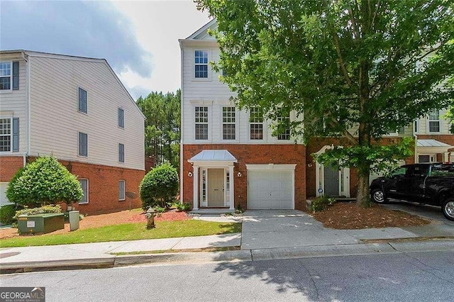 townhome / multi-family property with a garage, driveway, and brick siding