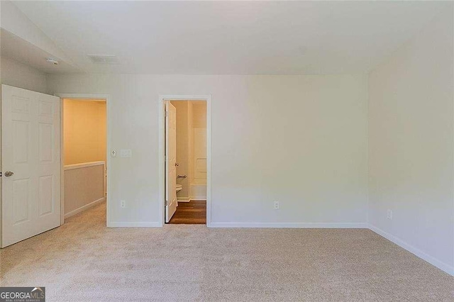 unfurnished bedroom featuring baseboards, carpet, and ensuite bath
