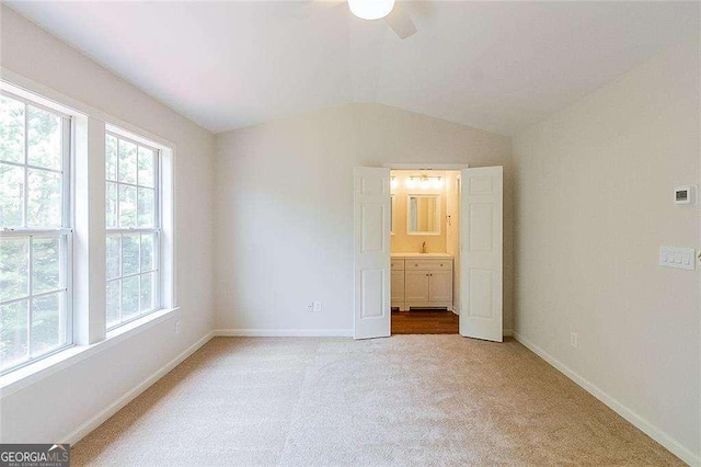 unfurnished bedroom with baseboards, light colored carpet, multiple windows, and lofted ceiling