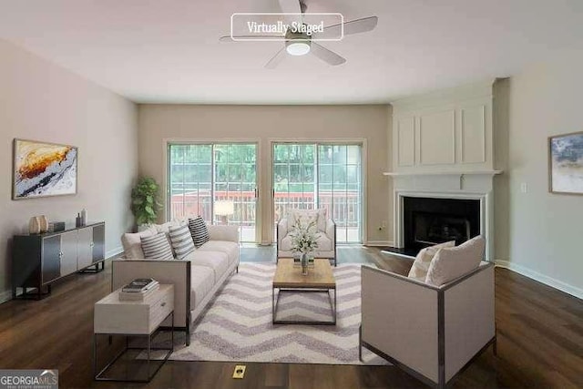 living area featuring baseboards, ceiling fan, wood finished floors, and a fireplace