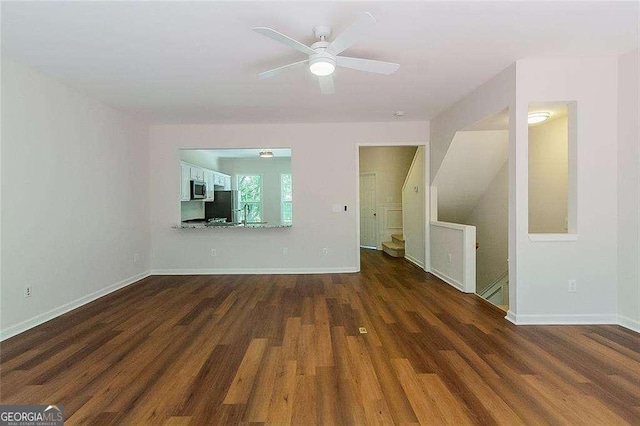 unfurnished living room with baseboards, ceiling fan, and wood finished floors
