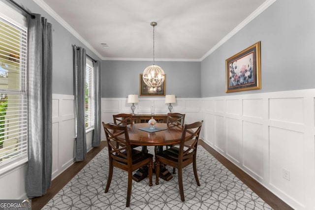 dining room with an inviting chandelier, ornamental molding, dark wood finished floors, and a decorative wall