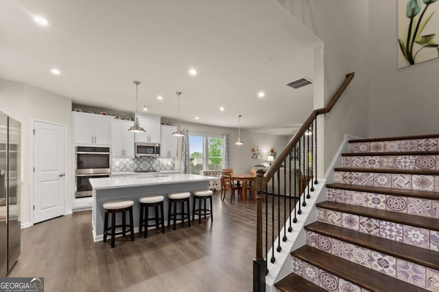 kitchen with backsplash, dark wood-style flooring, visible vents, appliances with stainless steel finishes, and white cabinetry
