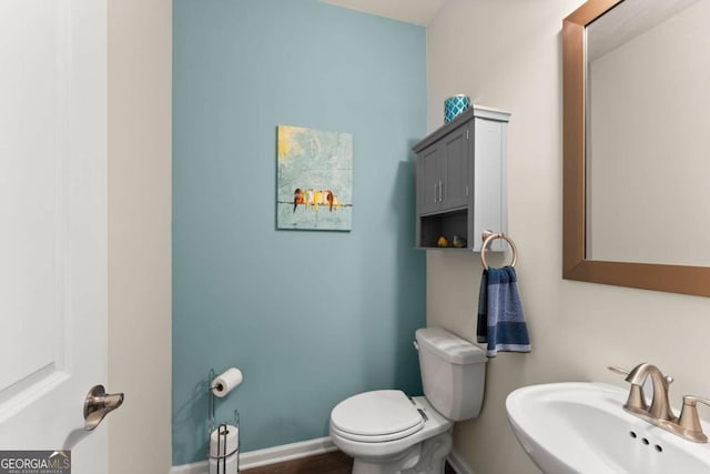 bathroom featuring baseboards, a sink, and toilet