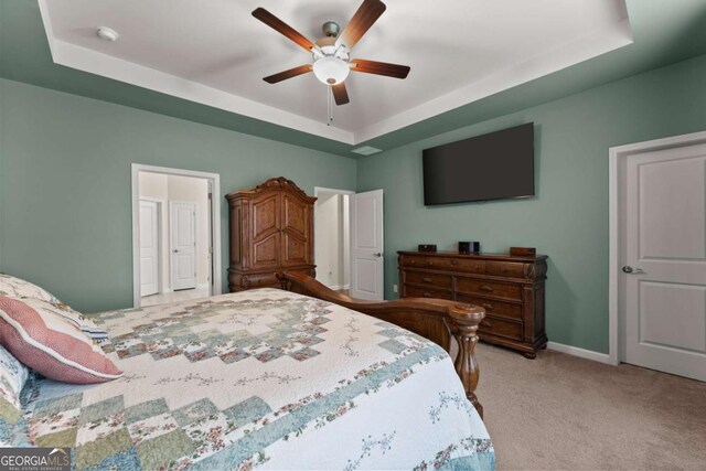 bedroom with light colored carpet, a raised ceiling, ceiling fan, and baseboards