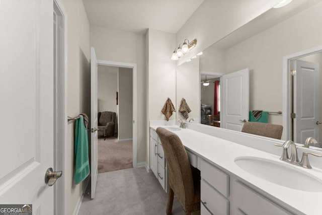 full bath featuring connected bathroom, double vanity, baseboards, and a sink