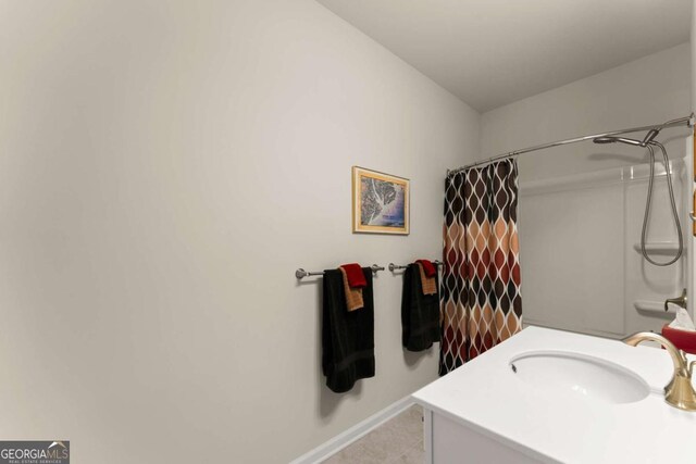 bathroom featuring baseboards, a shower with shower curtain, tile patterned floors, and vanity