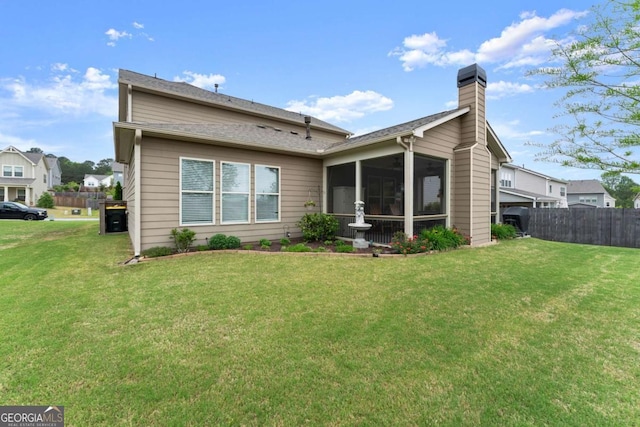 rear view of house featuring a lawn, a sunroom, fence, and a chimney