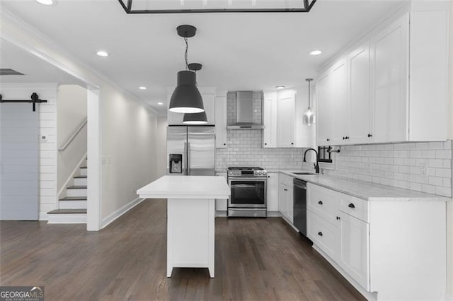 kitchen with wall chimney range hood, appliances with stainless steel finishes, a sink, light countertops, and white cabinetry