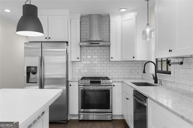 kitchen with wall chimney range hood, white cabinets, appliances with stainless steel finishes, a sink, and decorative backsplash