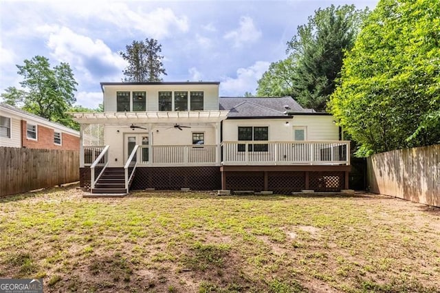 rear view of property with a lawn, a deck, a ceiling fan, and a fenced backyard