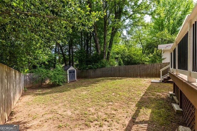 view of yard featuring an outbuilding, a fenced backyard, and a storage unit