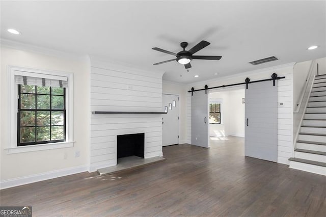unfurnished living room with visible vents, ornamental molding, ceiling fan, stairway, and a barn door