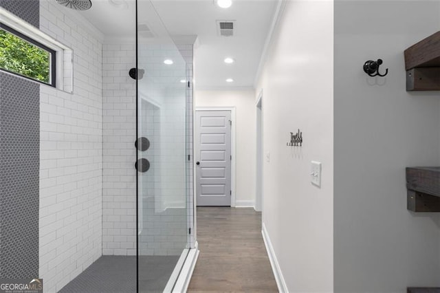 full bath featuring visible vents, ornamental molding, wood finished floors, and tiled shower