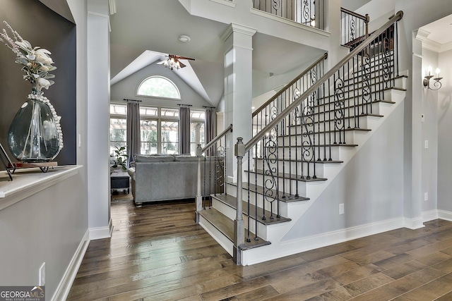 stairs with baseboards, ceiling fan, wood finished floors, and high vaulted ceiling