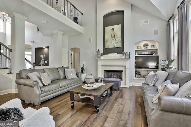 living area featuring dark wood-style floors, high vaulted ceiling, visible vents, and built in shelves