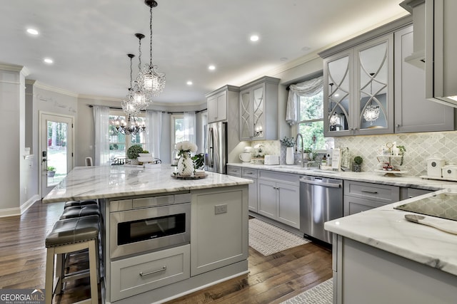 kitchen featuring crown molding, appliances with stainless steel finishes, a sink, dark wood finished floors, and gray cabinets