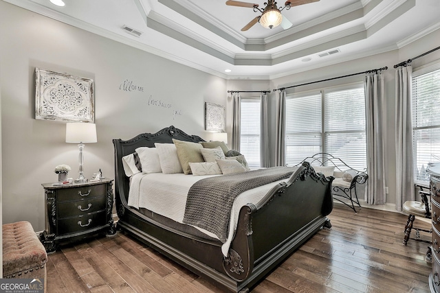 bedroom with crown molding, a raised ceiling, and dark wood-type flooring