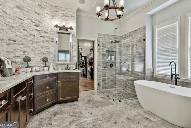 full bathroom with crown molding, double vanity, an inviting chandelier, a soaking tub, and a shower stall