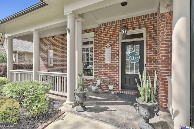property entrance featuring covered porch and brick siding