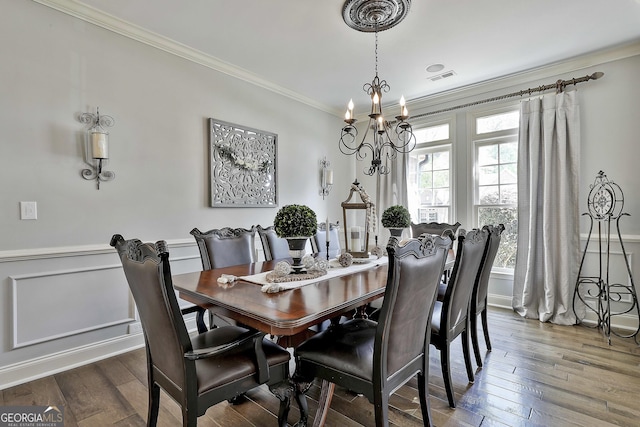 dining room featuring crown molding, a notable chandelier, visible vents, and hardwood / wood-style floors