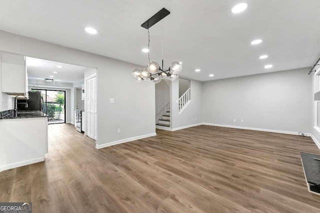 unfurnished dining area featuring stairway, baseboards, recessed lighting, and wood finished floors