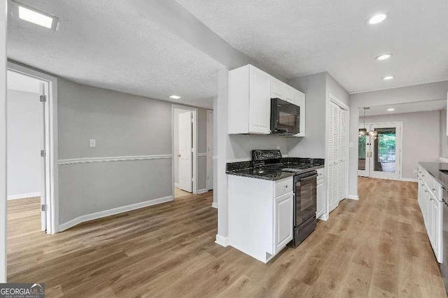kitchen with white cabinets, baseboards, black appliances, and light wood-style floors
