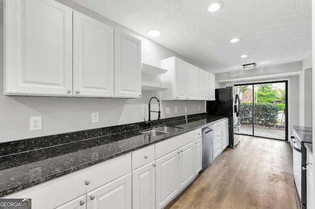 kitchen with stainless steel dishwasher, open shelves, white cabinetry, a sink, and light wood finished floors
