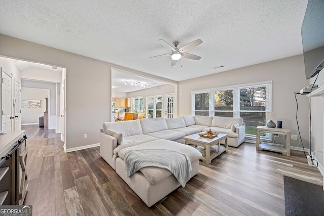 living area with ceiling fan, wood finished floors, a textured ceiling, and baseboards