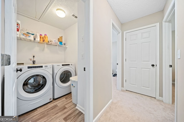 washroom featuring washing machine and dryer, a textured ceiling, attic access, and baseboards