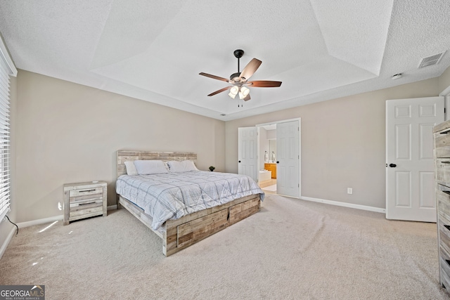 bedroom with light carpet, baseboards, a textured ceiling, ceiling fan, and ensuite bath
