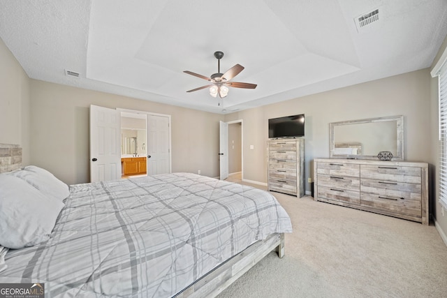 bedroom featuring a raised ceiling, light carpet, baseboards, and ceiling fan