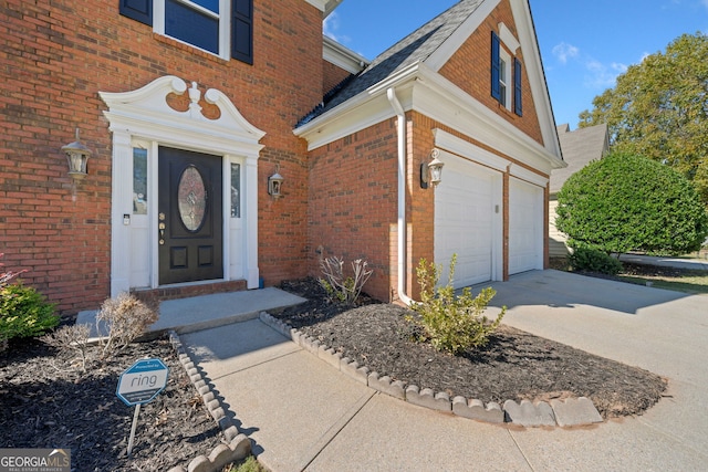 entrance to property with a garage, brick siding, and driveway