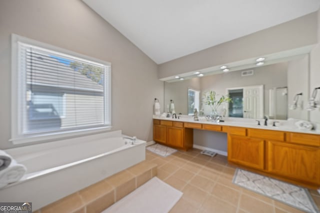 bathroom featuring vaulted ceiling, a garden tub, double vanity, and tile patterned floors