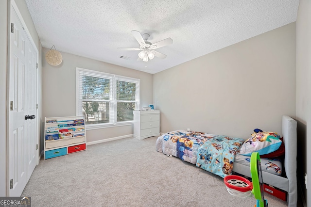 carpeted bedroom featuring a textured ceiling, baseboards, a ceiling fan, and a closet