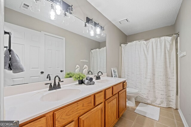 full bath featuring double vanity, toilet, tile patterned flooring, a textured ceiling, and curtained shower