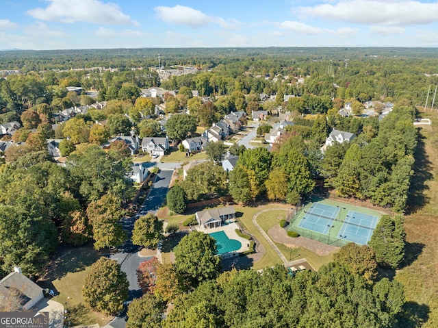 aerial view of property and surrounding area with a forest and a pool area