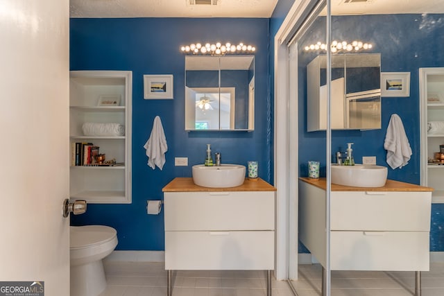 bathroom with tile patterned flooring, built in features, two vanities, and baseboards