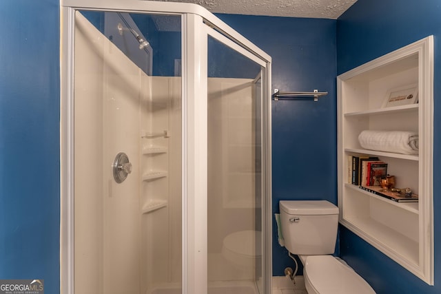 bathroom featuring a stall shower, toilet, and a textured ceiling