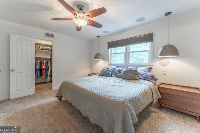 bedroom featuring light carpet, a spacious closet, ceiling fan, a closet, and baseboards