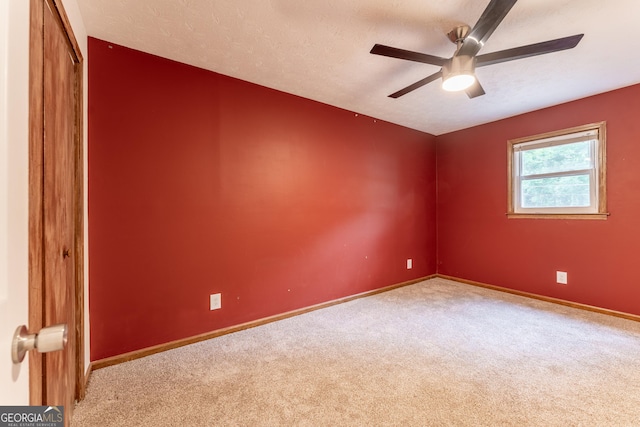 spare room with carpet floors, a ceiling fan, baseboards, and a textured ceiling
